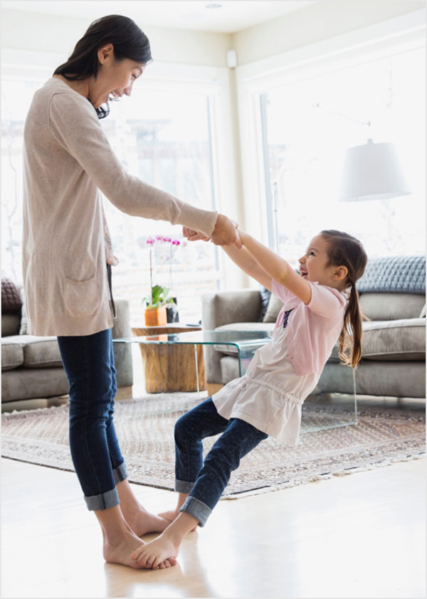 Mother and daughter dancing in living room