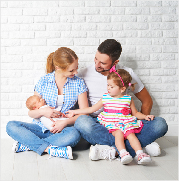 Couple in new home holding toddler and baby