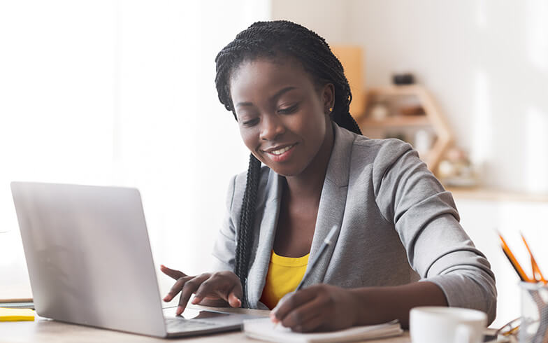 Young woman making notes on personal finances from laptop