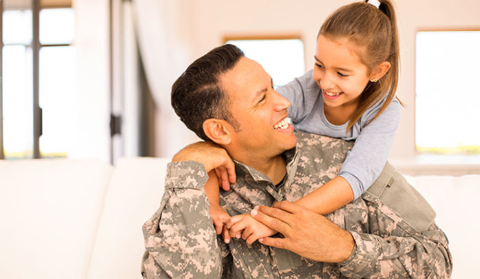 Uniformed dad holding daughter on shoulders