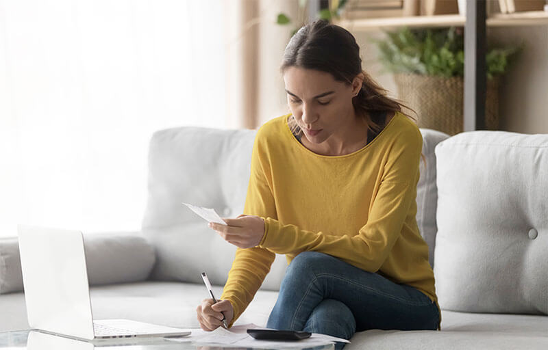 Woman reviewing personal finances with laptop and calculator