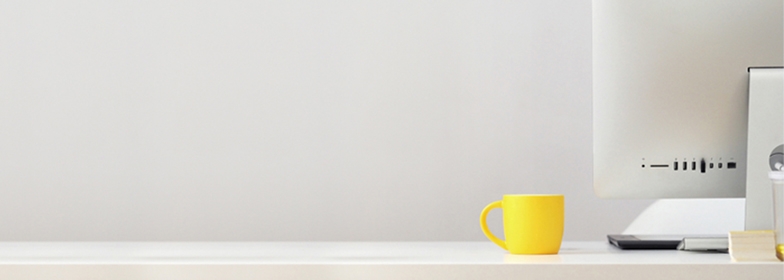 iMac and yellow coffee cup on clean desk