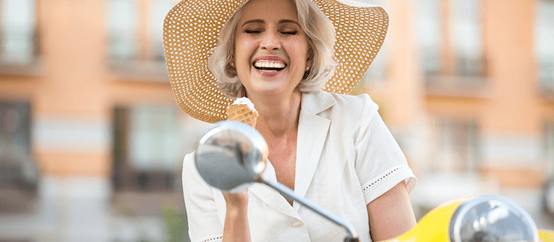 Older woman on Vespa enjoying ice cream