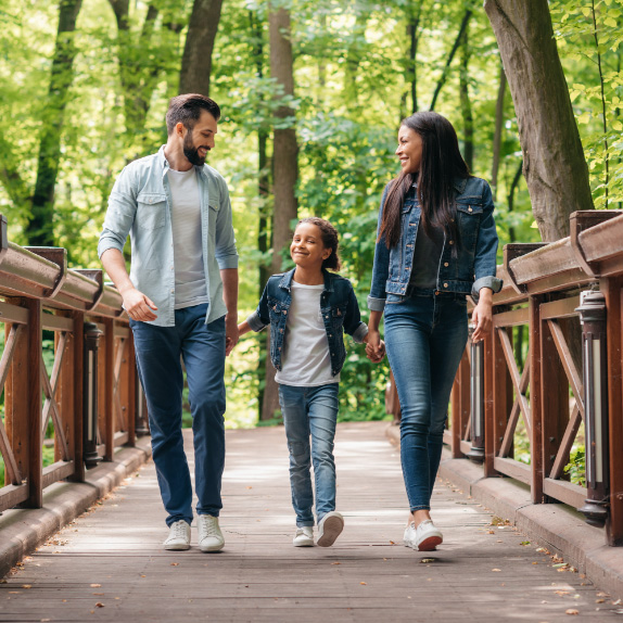 Family holding hands walking across a bridge