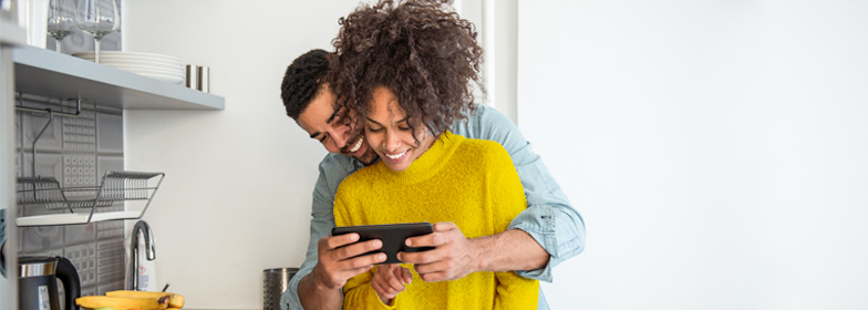 Couple looking at home options together on phone in their kitchen