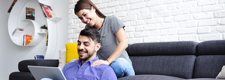 Smiling couple sitting on couch reading on a tablet