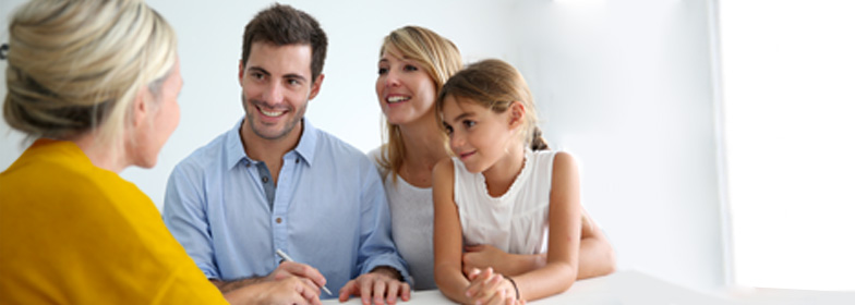 Smiling couple with child talking to assistant