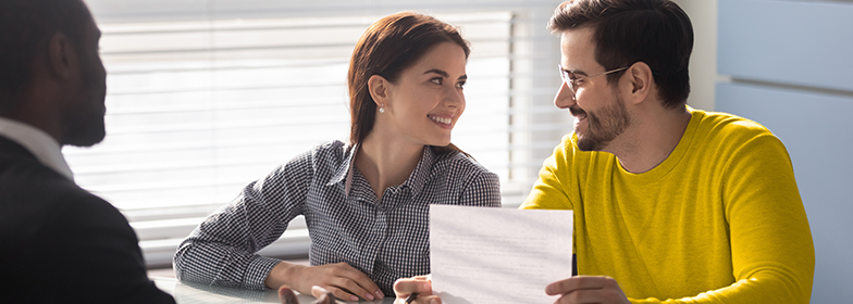 Two people smiling at each other while looking over a document.