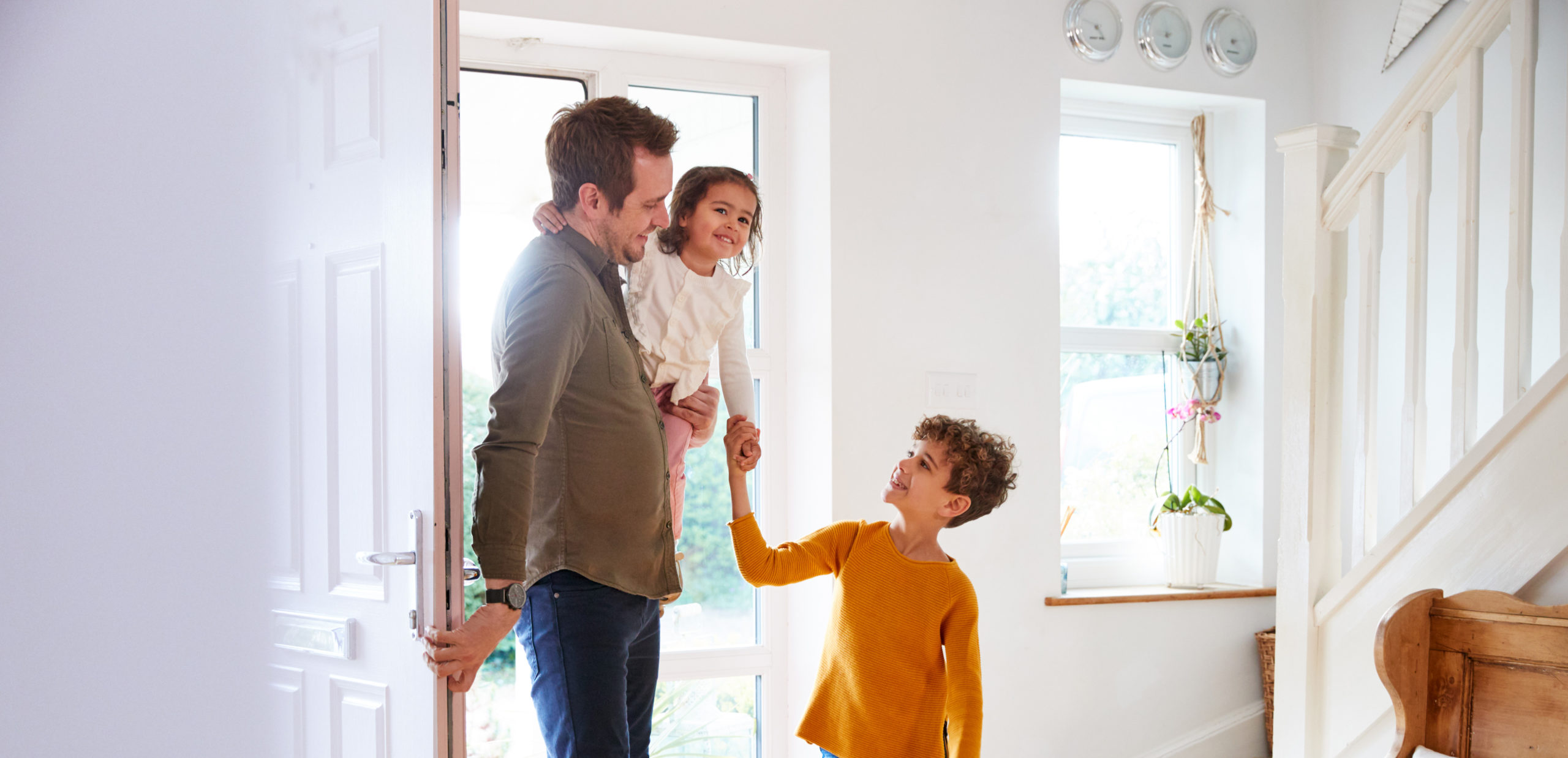 A father greeted by his children at the front door