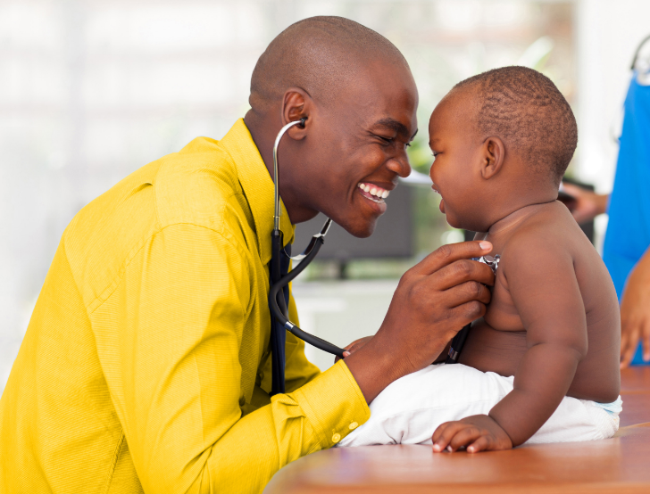 Smiling doctor using stethoscope to perform checkup on happy baby