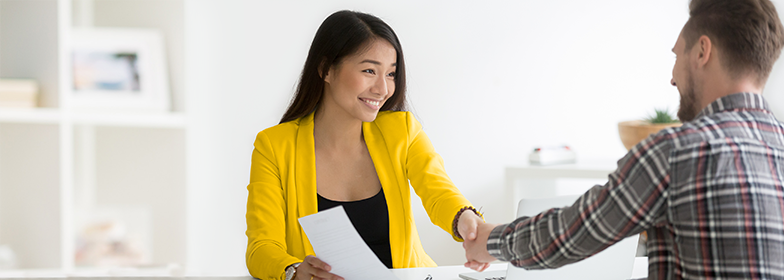 A woman shaking hands after signing a deal