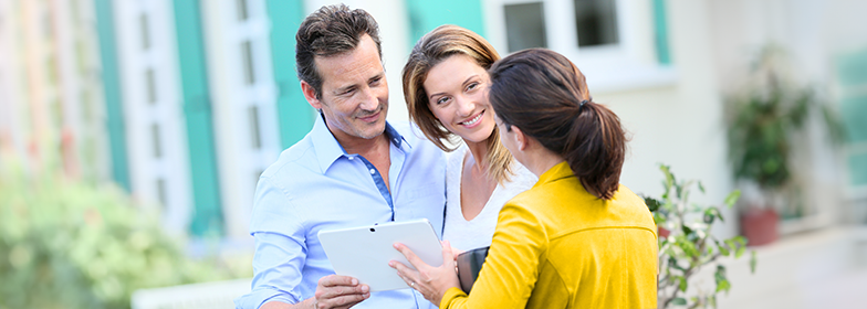 Happy couple looking at tablet with Loan Officer